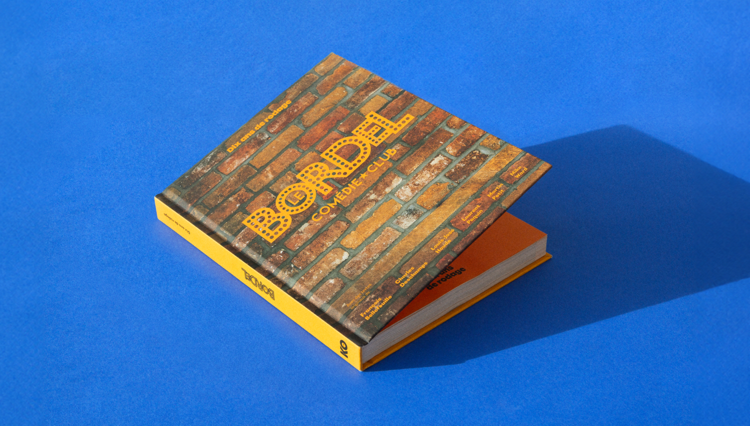 Vue en angle du livre fermé sur un fond bleu vibrant, soulignant le design robuste et iconique de l'ouvrage.