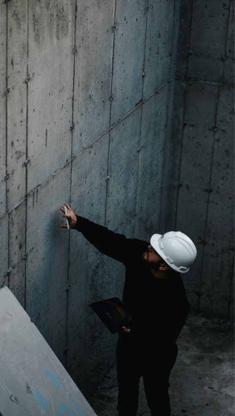 Ingénieur en casque de sécurité inspectant un mur en béton, mettant en évidence l'expertise et l'approche pratique de la firme Solid.