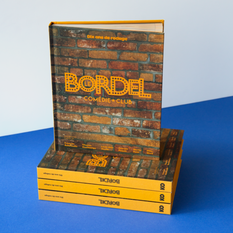 Photographie du livre « Dix ans de rodage » posé sur une pile, mettant en valeur sa couverture texturée à effet de briques et le nom des fondateurs.