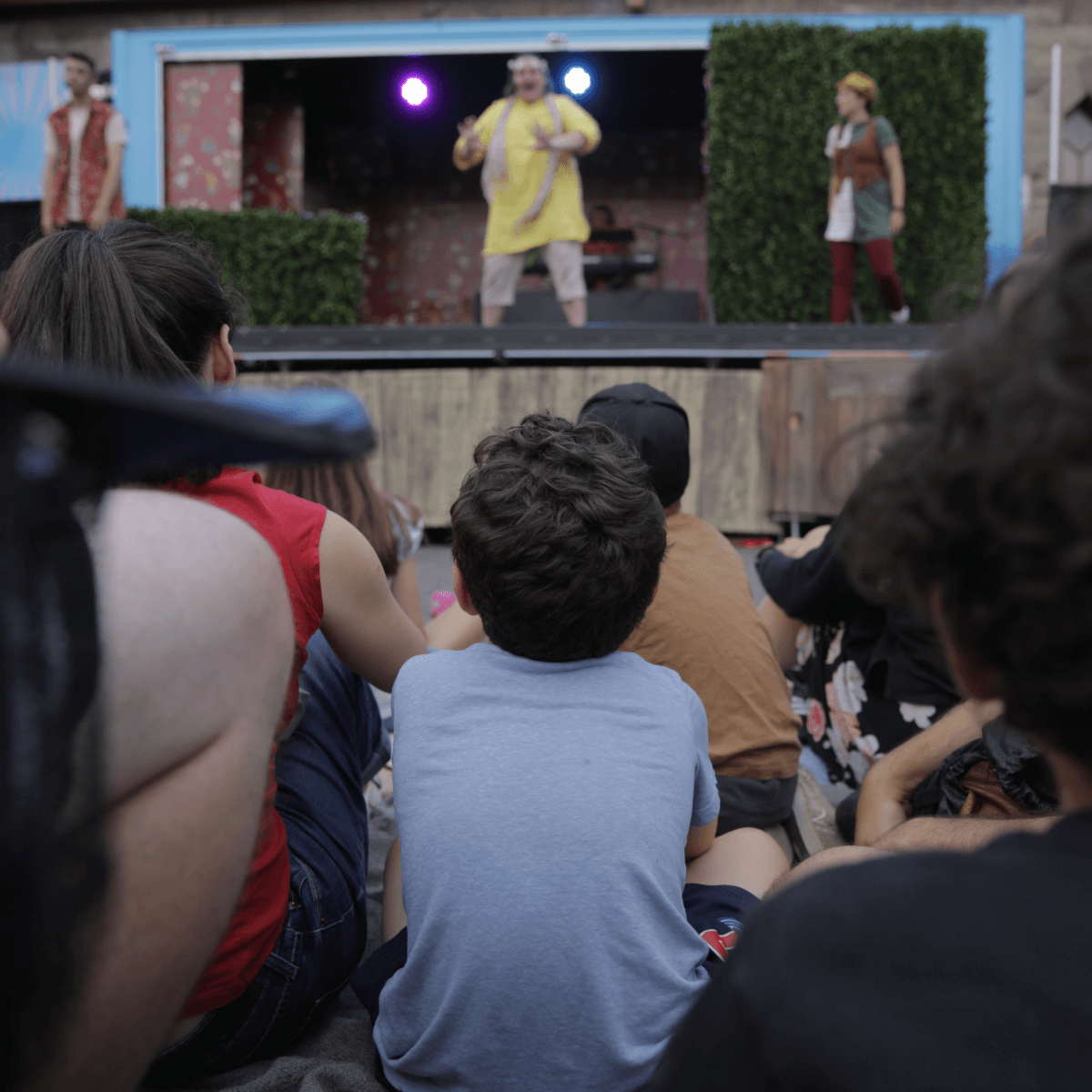 Photo d'une scène de théâtre jeunesse vue de dos par un enfant, illustrant l'ambiance des spectacles de l'Arrière Scène 2025-2026.