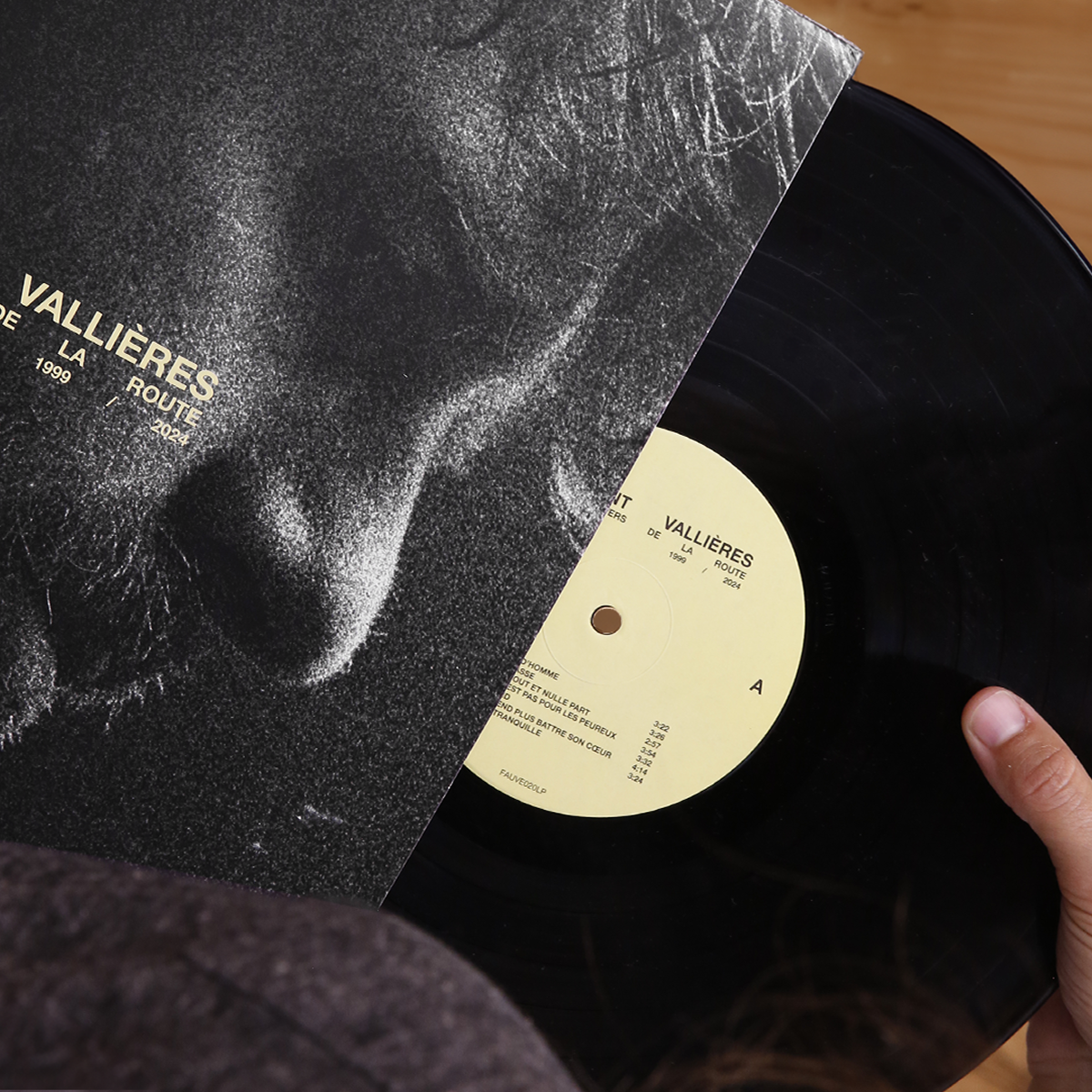 Plan rapproché focalisé sur la texture de la pochette et l'ouverture du disque. L'angle de vue permet d'apprécier la qualité du carton et l'aspect tangible de l'objet vinyle partiellement sorti.