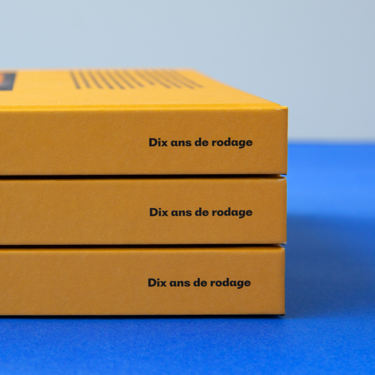 Détail de la tranche jaune du livre montrant la répétition du titre « Dix ans de rodage » sur une pile d'exemplaires.